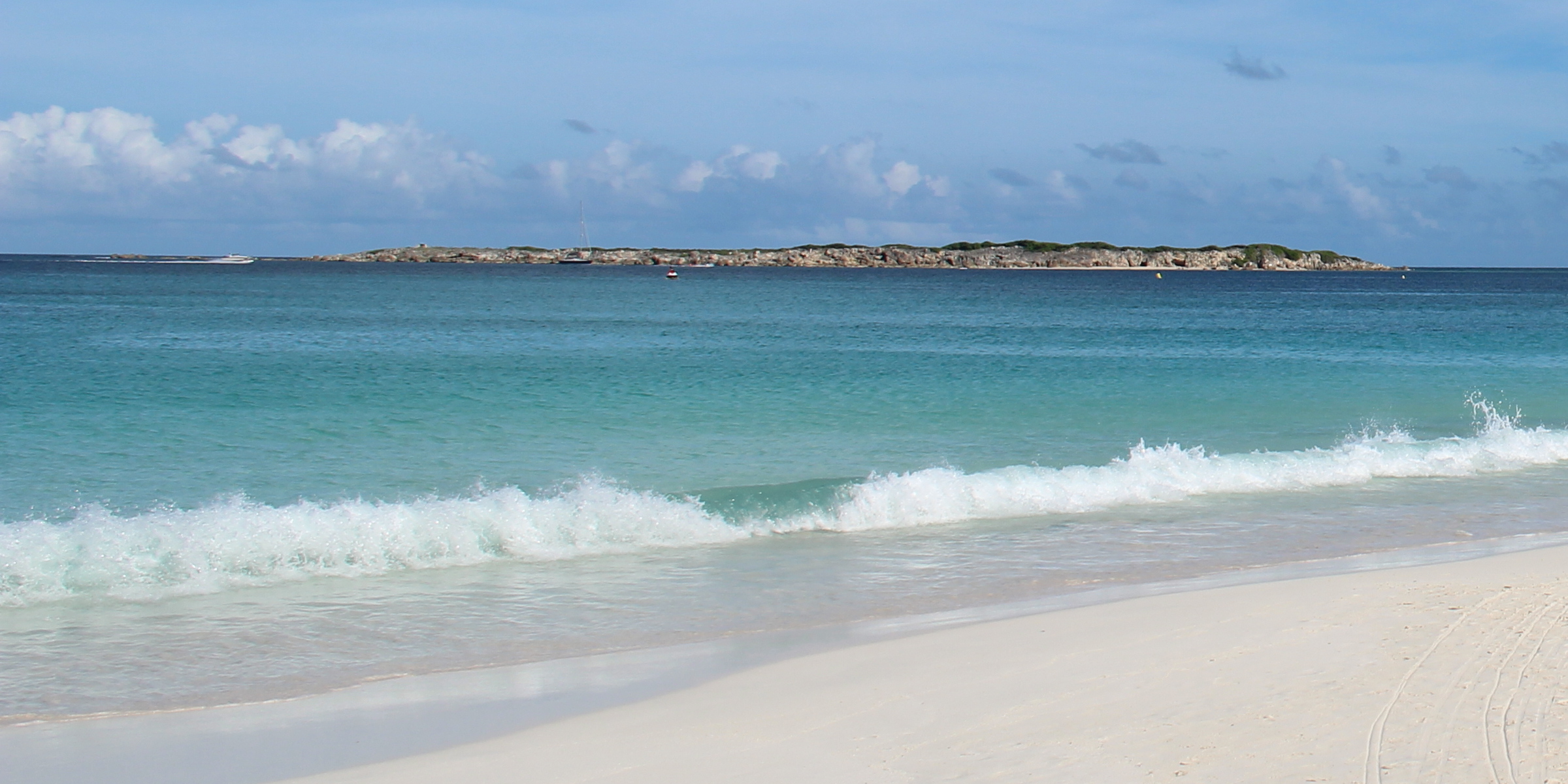 Orient Bay beach with waves and Caye Verte islet offshore, Saint-Martin